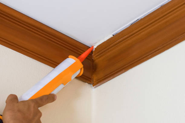Caulking gun Technician man hand using glue gun or manual caulking gun with polyurethane silicone to repair and fix the wooden cornice with the ceiling. Installation or renovation interior concept. architectural cornice stock pictures, royalty-free photos & images