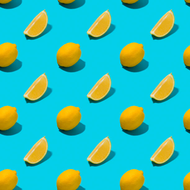Whole and sliced lemon in a row on turquoise background.