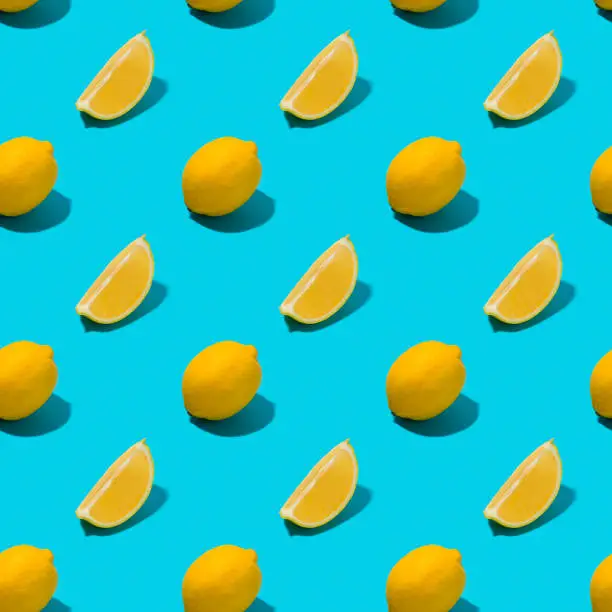 Photo of Whole and sliced lemon in a row on turquoise background.