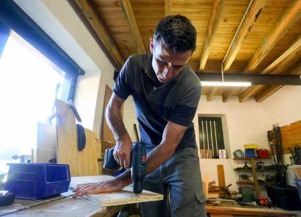 istock A carpenter working in his work shop. He is busy with his hand drill. 1262618624