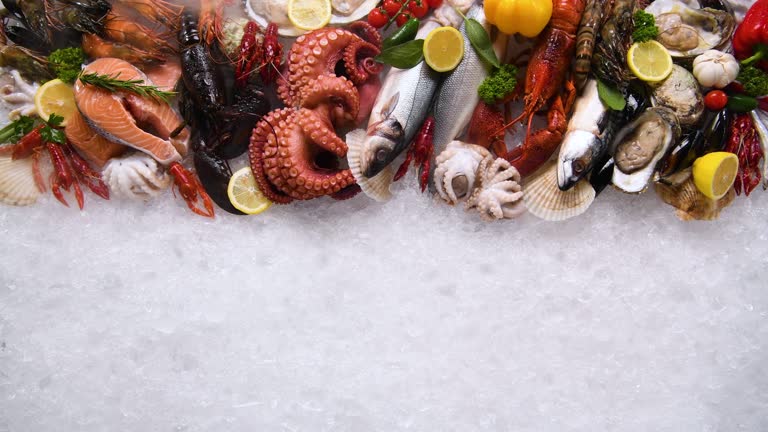 Top view of variety of fresh fish and seafood on ice with dry ice smoke.