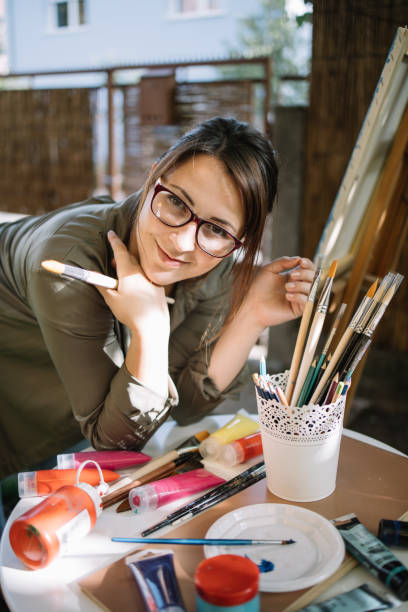 istock Female artist posing on table with paint brushes and paint tubes 1262623189