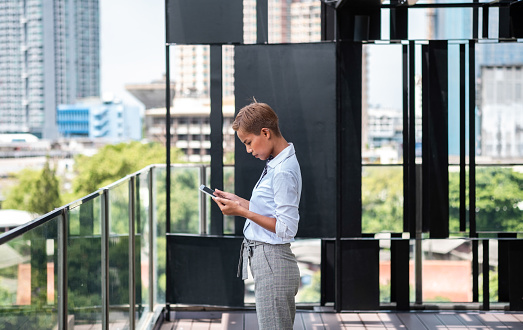 Business woman using digital tablet with office building in the background
