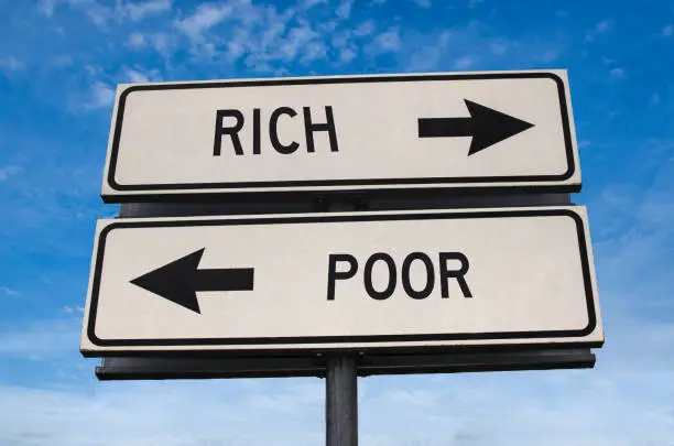 Photo of Rich and poor road sign. White two street signs with arrow on metal pole with word