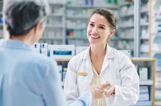 Shot of a young pharmacist assisting a mature woman in a chemist