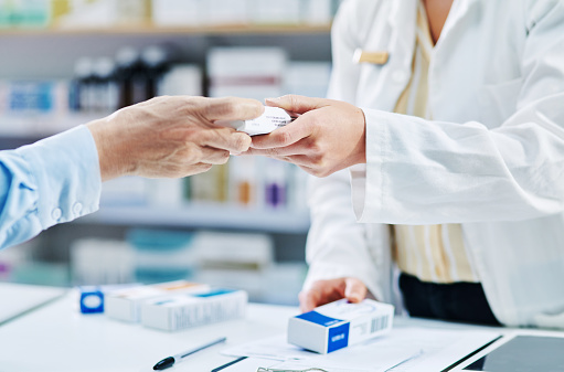 Shot of a pharmacist handing a customer a box of medication in a chemist