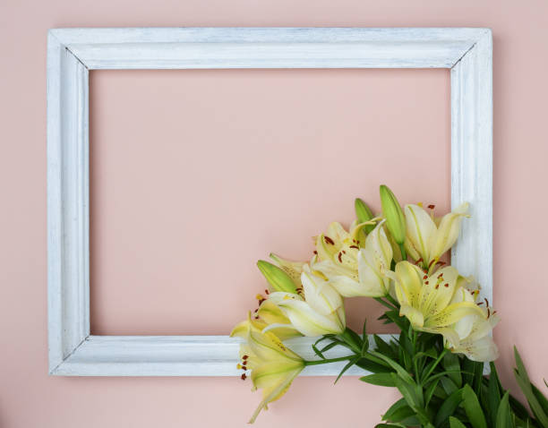 istock Creative card with fresh white lilies and picture frame on pastel pink background 1262629435