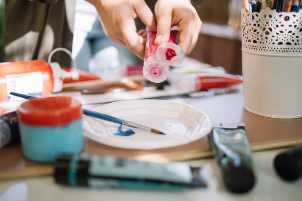 istock Female hands squeezing red aquarelle paint tube 1262630876