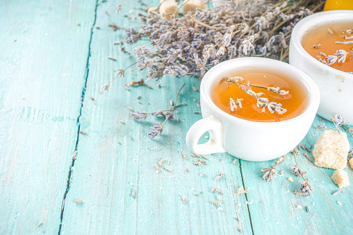 Aromatic lavender tea cup, with and bunch of lavender, honey and lemon, turquoise wooden background copy space