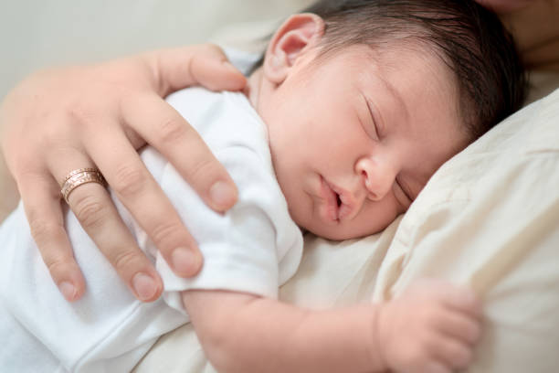 istock Mother hugging newborn baby boy while sleeping peacefully 1262634036
