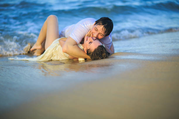istock newlywed in wet clothes flirting lying on beach. 1262648263