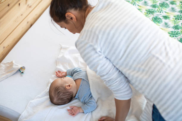 istock Mother standing over her baby boy and looking how he sleeps 1262651908