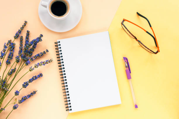istock Mock up with blank notepad on yellow background with lavender flowers, coffee cup, pen and glasses. Top view, flat lay 1262652133