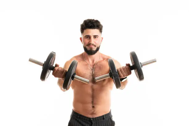 Handsome bearded power man fitness-model with six packs is training with dumbbells, isolated on white background with copyspace