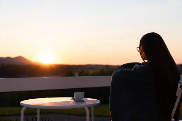 istock Woman alone on terrace watching sunset over mountains during summer vacation 1262656220