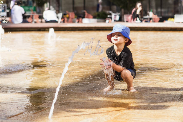 istock Little boy playing with water jet in fountain 1262660372