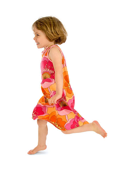 Small child running across white background in dress stock photo