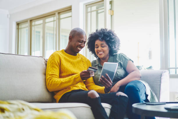 istock Smiling couple sitting on their living room sofa and using a tablet 1262663860
