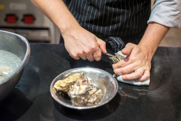 istock Chef trying to opened fresh oyster in restaurant kitchen 1262663942
