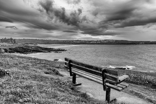 Park bench overlooking the sea at Newquay, Cornwall.  A moody and dark treatment in black and white.