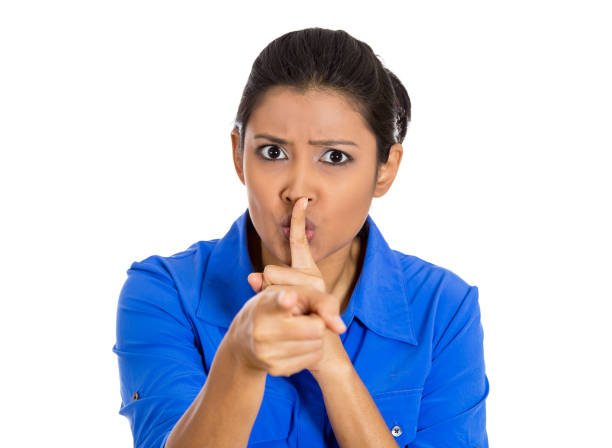 istock serious woman placing finger on lips, pointing at you quiet, silence 1262670509