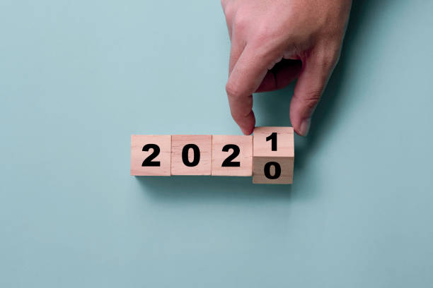 cubos de madeira de lançamento à mão bloqueiam para mudar de 2020 para 2021.  feliz ano novo para começar novo projeto e conceito de negócio. - the end fotos - fotografias e filmes do acervo