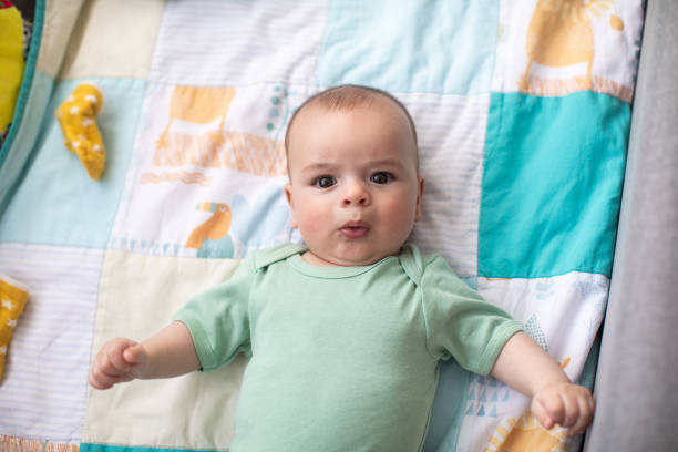 istock Cute baby boy lying on back in crib, looking at camera and making funny face 1262671681