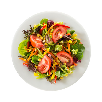 Fresh salad with tomato, red leaf lettuce, sweetcorn, peppers, basil leaves, carrot and olive oil served on white bowl and white background. Isolated salad on white background.