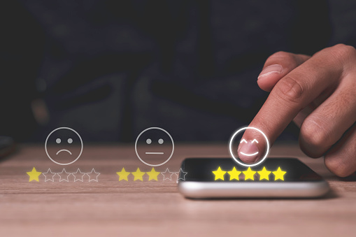 Hand touch on mobile phone to add five yellow stars to customer evaluates products and services. Customer satisfaction and marketing survey rating concept.