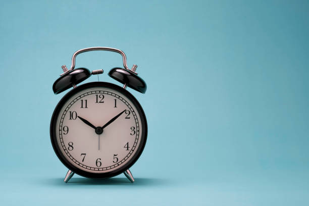 istock closeup of beautiful black alarm clock on green background wit copy space. 1262673751