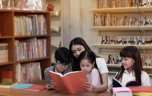 istock The beautiful lady reading book with three children with happy feeling,blurry light around 1262679985