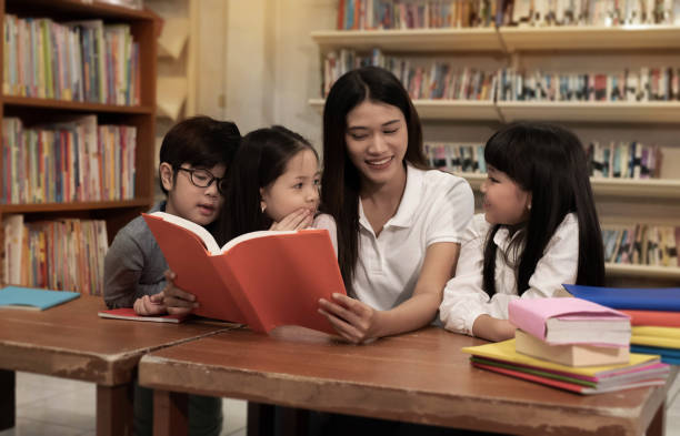 istock The beautiful lady reading book with three children with happy feeling,blurry light around 1262679987