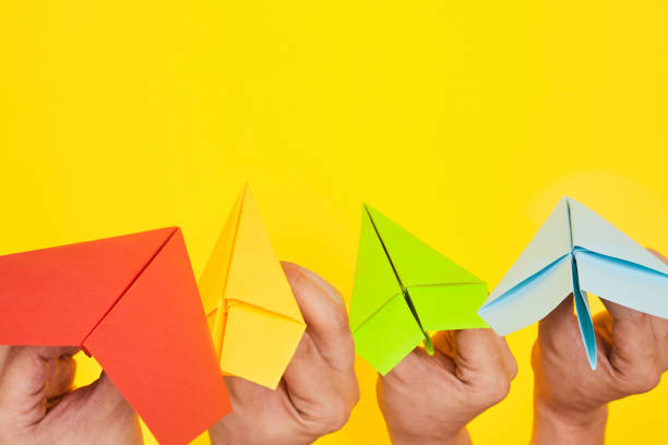 istock Hands throw paper planes multicolored on yellow background copy space one 1262680192