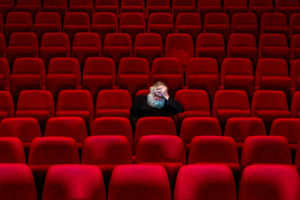 istock One man with white beard sits in Empty cinema or theatre with comfortable red seats, sleeping 1262680207