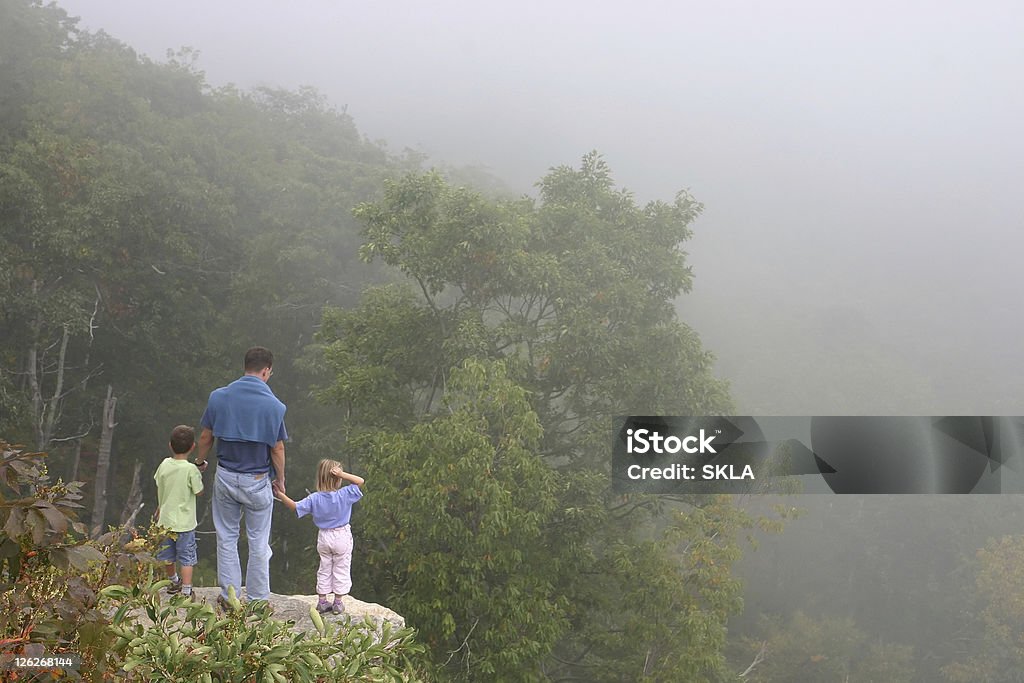 Escursione famiglia-Padre con due bambini in piedi sulla roccia - Foto stock royalty-free di Adulto