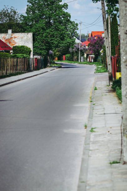 Asphalt road across village next to fences and houses