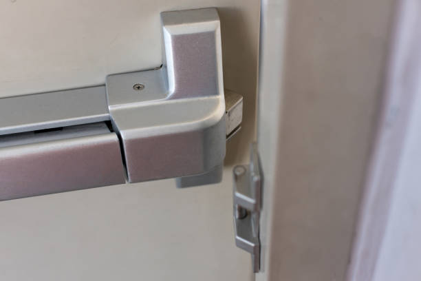 istock Emergency fire exit door. Closed up latch and rusty door handle of emergency exit. Push bar and rail for panic exit. Open one way door.  steel of handle for the white door fire exit 1262683527