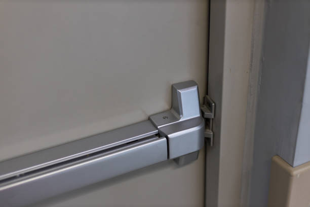 istock Emergency fire exit door. Closed up latch and rusty door handle of emergency exit. Push bar and rail for panic exit. Open one way door.  steel of handle for the white door fire exit 1262683543