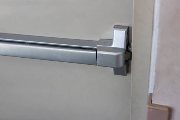 istock Emergency fire exit door. Closed up latch and rusty door handle of emergency exit. Push bar and rail for panic exit. Open one way door.  steel of handle for the white door fire exit 1262683617