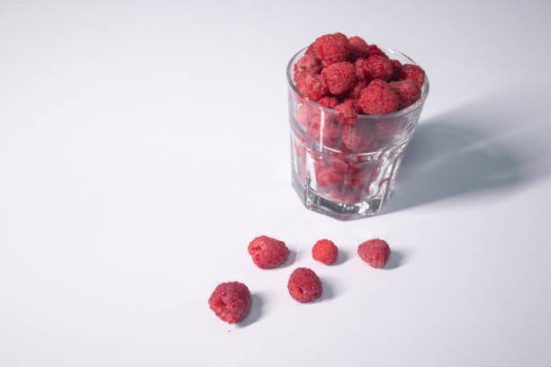 istock transparent glass with raspberries on white table in gray kitchen 1262687101