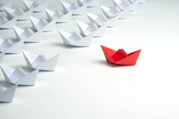 istock Leadership concept. Red leader paper ship leading among white ships. 1262689103