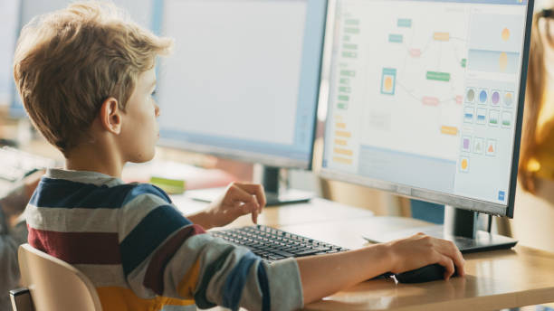 istock Elementary School Computer Science Classroom: Smart Little Schoolboy Works on Personal Computers, Learning Programming Language for Software Coding. Schoolchildren Getting Modern Education 1262689190