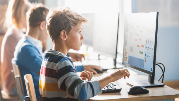 istock Elementary School Science Classroom: Smart Little Schoolchildren Sitting in Row and Work on Personal Computers, Learn Programming Language for Software Coding. Schoolchildren Getting Modern Education 1262689223