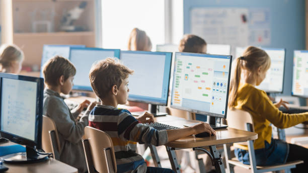 小学校のコンピュータサイエンス教室:スマート小学生はパーソナルコンピュータで働き、ソフトウェアコーディングのためのプログラミング言語を学びます。現代教育を受ける小学生 - elementary student little boys classroom child ストックフォトと画像