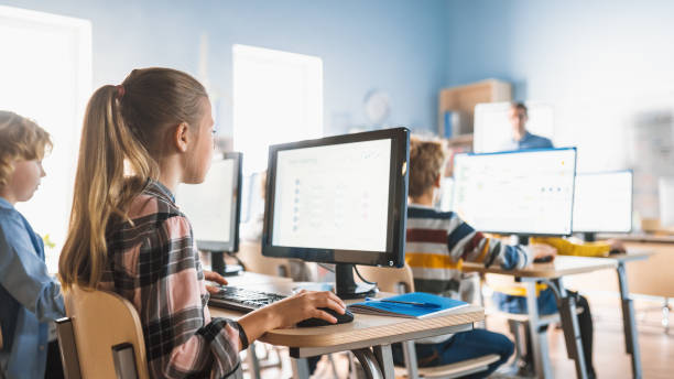 小学校のコンピュータサイエンス教室:かわいい女の子は、ソフトウェアコーディングのためのプログラミング言語を学習し、パーソナルコンピュータを使用しています。現代教育を受ける小 - elementary student little boys classroom child ストックフォトと画像