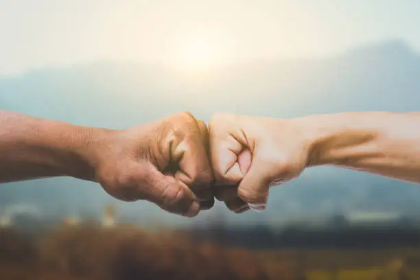 Photo of Man giving fist bump in sun rising nature background. power of teamwork concept. vintage tone