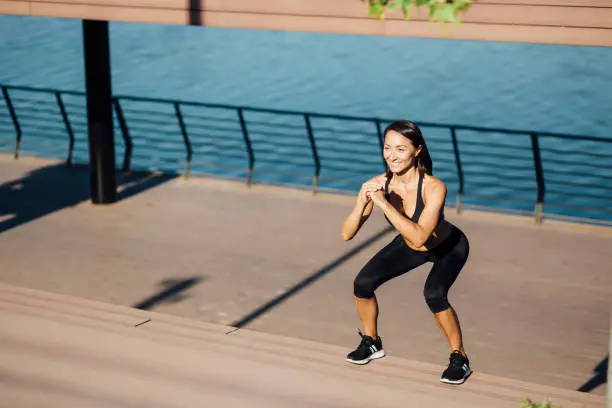 Beautiful and handsome young Caucasian woman exercising outdoors next to a river and on top of the staircase, staying in shape