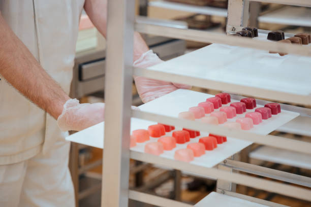 istock Hands in gloves putting tray with ruby truffles on shelf 1262691185