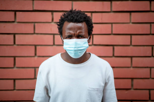 istock African-American young man with protective face mask frowning at camera 1262691900