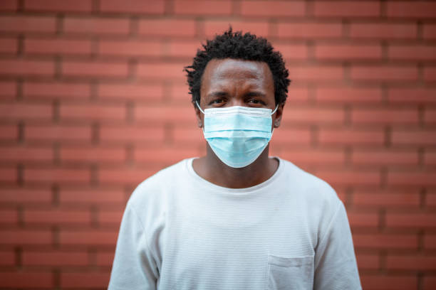 istock African-American young man with protective face mask looking at camera with blank expression 1262691905